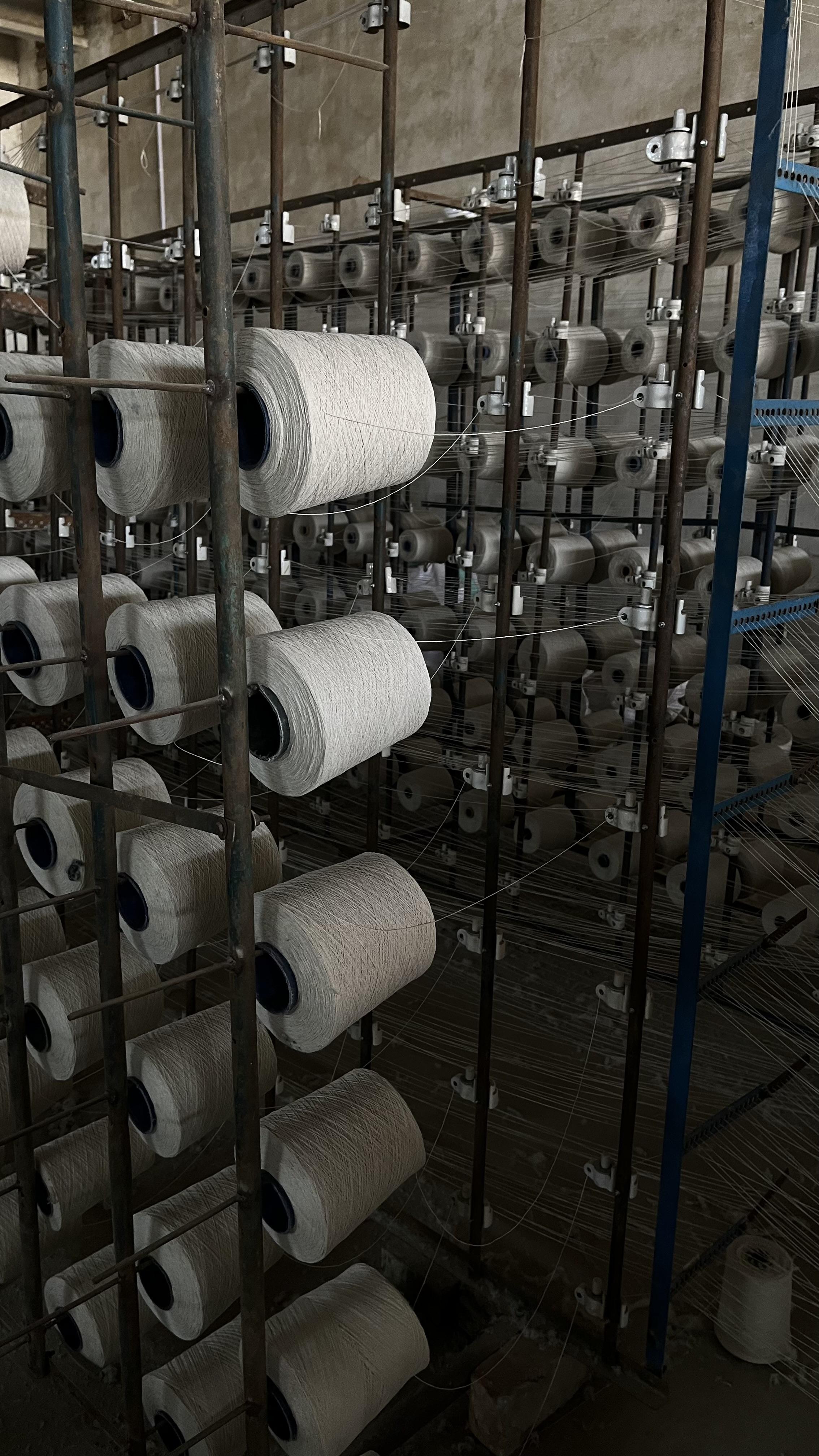 Cotton yarn cones on a creel, feeding warp threads at the Siraj Textile factory